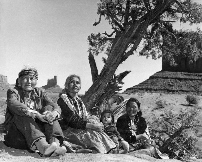 Navajo family sitting on ground by tree. Monument Valley, 1960's